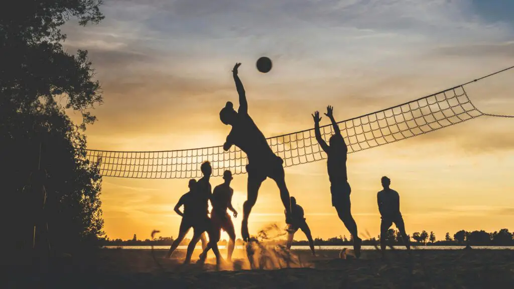 Active Sports and Recreational Outings: Get Your Heart Racing with Fun Group Activities for Adults in Chicago Group of young adults playing volleyball on a sandy court, enjoying an active sports outing in Chicago.