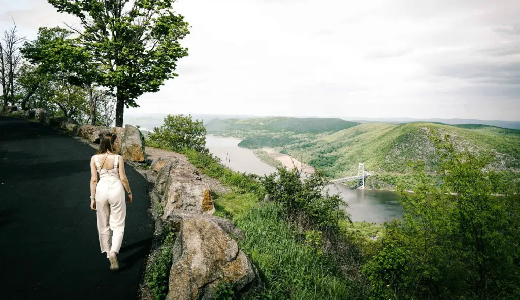 Embracing Outdoor Adventures and Nature Escapes Young woman standing at a scenic overlook, admiring a river and bridge surrounded by nature in Rockford, Illinois.