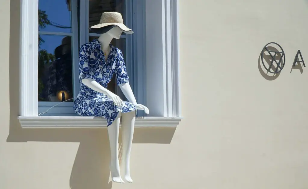 Tailored Outings for Different Age Groups Well-dressed female mannequin wearing a sun hat, seated in a store window display in Rockford, Illinois.