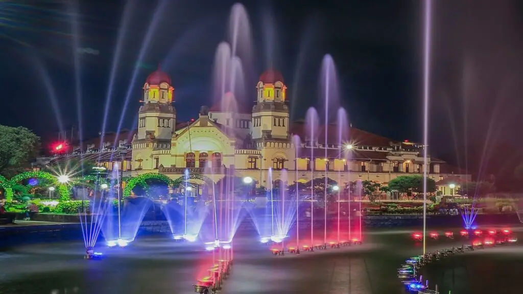 Nighttime view of Epic Universe in Orlando, illuminated with vibrant lights and attractions in full swing.