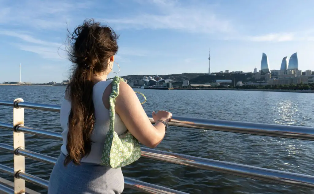 Outdoor and Urban Adventures: Things to Do in NYC Labor Day Weekend Young woman standing on a boardwalk in NYC, gazing out at the ocean under a clear sky during Labor Day weekend.