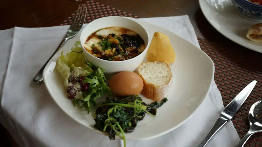 A warm bowl of soup with egg and fresh vegetables, served in a cozy Fort Greene restaurant.
