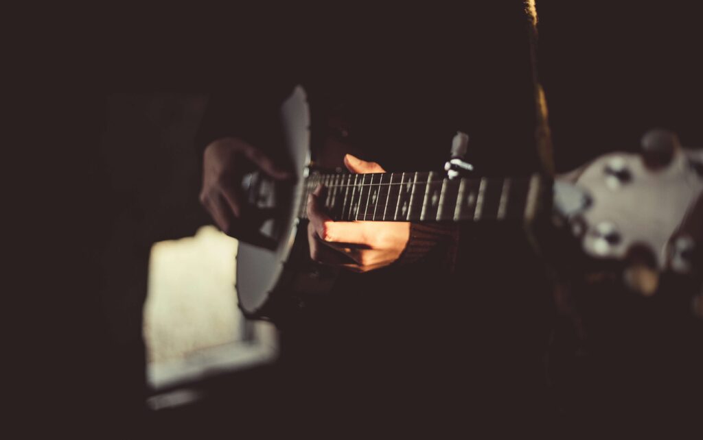 Close-up of a hand playing a guitar, symbolizing East Village’s vibrant indie music and performance scene.