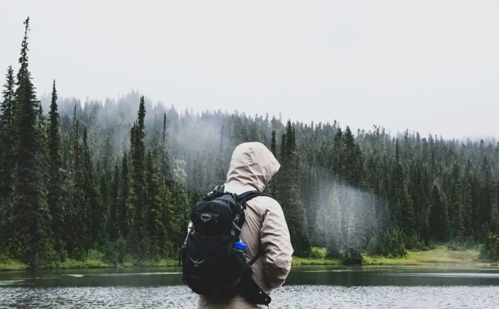 Outdoor Adventures and Hidden Green Spaces: Activities in the Lower East Side Traveler in a hooded jacket standing by a lake surrounded by trees on a cloudy day, discovering a quiet green space in the Lower East Side.