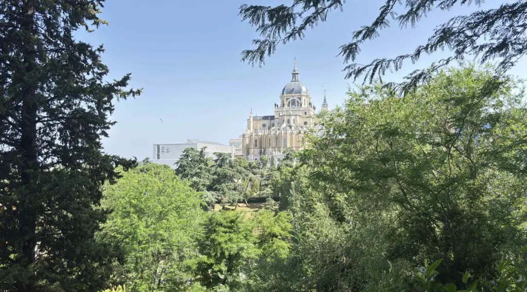 Discover Almudena Cathedral’s Facade: Cultural Immersion in Madrid Stunning view of Almudena Cathedral’s grand facade under a bright sky, highlighting its intricate architecture in Madrid.