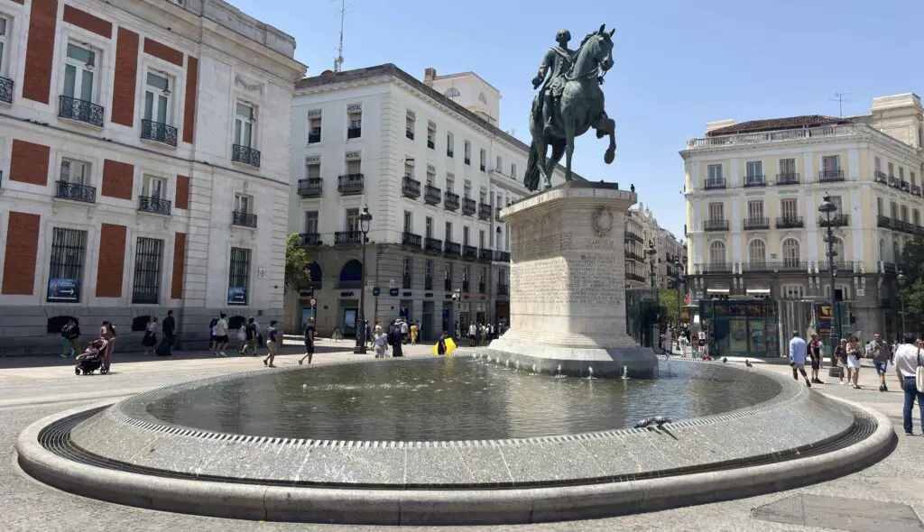 The new statue in Puerta del Sol, Madrid, standing prominently in the plaza with people walking around and historic buildings in the background.
