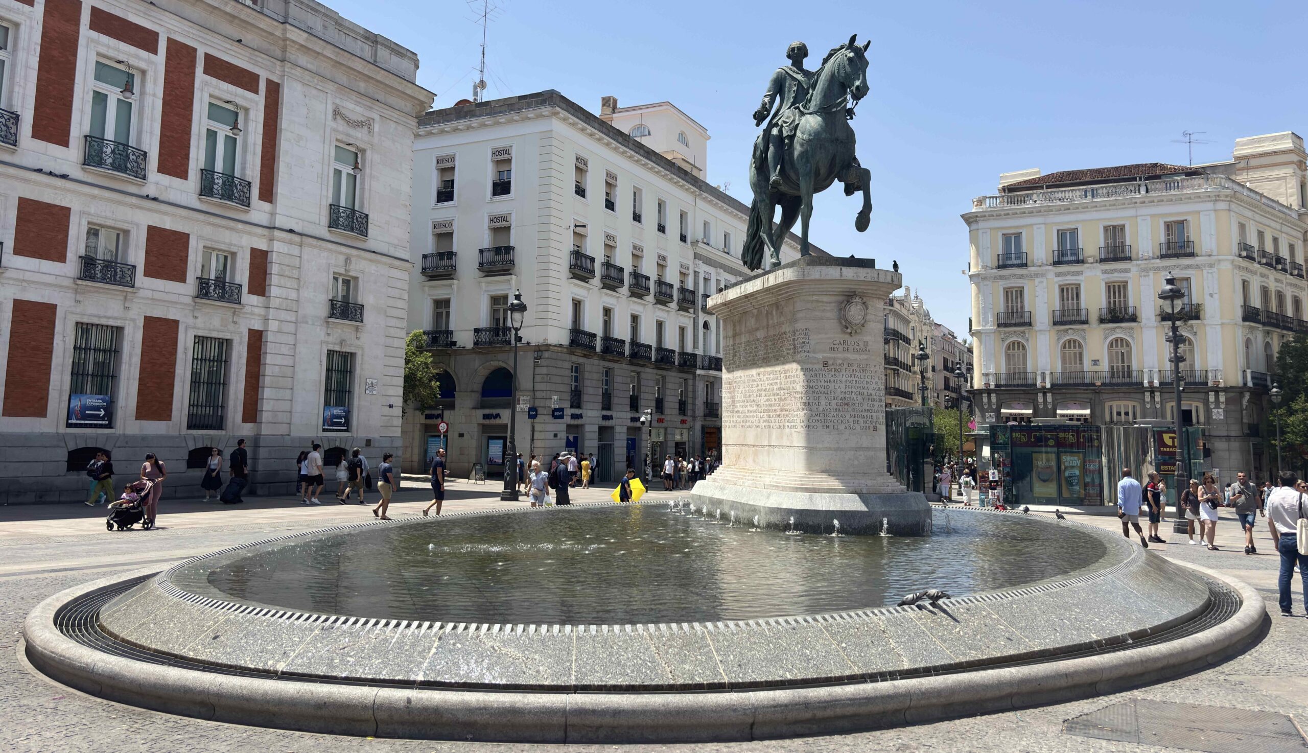 The new statue in Puerta del Sol, Madrid, standing prominently in the plaza with people walking around and historic buildings in the background.