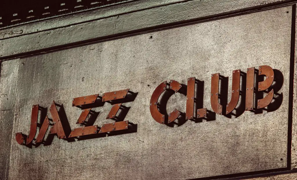 Feel the Rhythm: Best Jazz Bars in Greenwich Village for Tourists Dimly lit jazz bar in Greenwich Village with a live band performing on stage and an intimate crowd enjoying the music.
