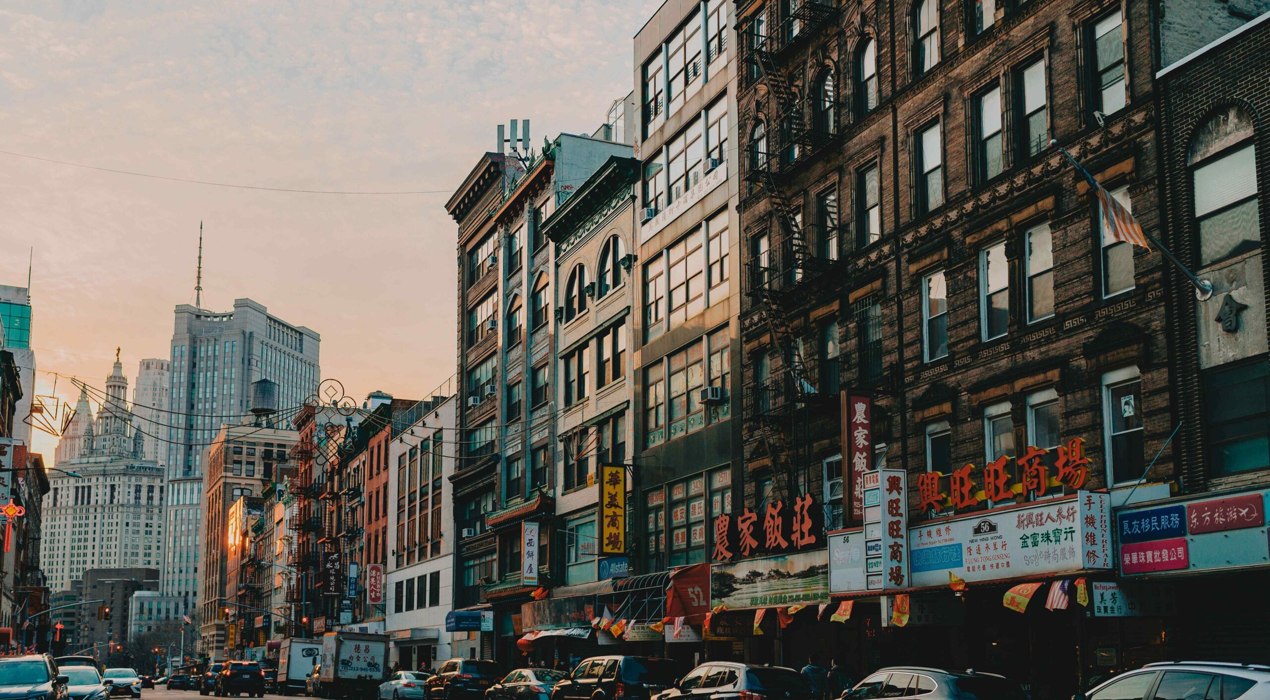 Street view of Chinatown NYC with traditional Chinese lanterns, storefront signs in Chinese characters, and people walking through the lively neighborhood.