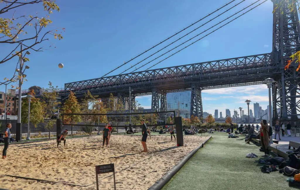 Group of friends playing volleyball on indoor sand courts, enjoying a fun activity in Brooklyn.